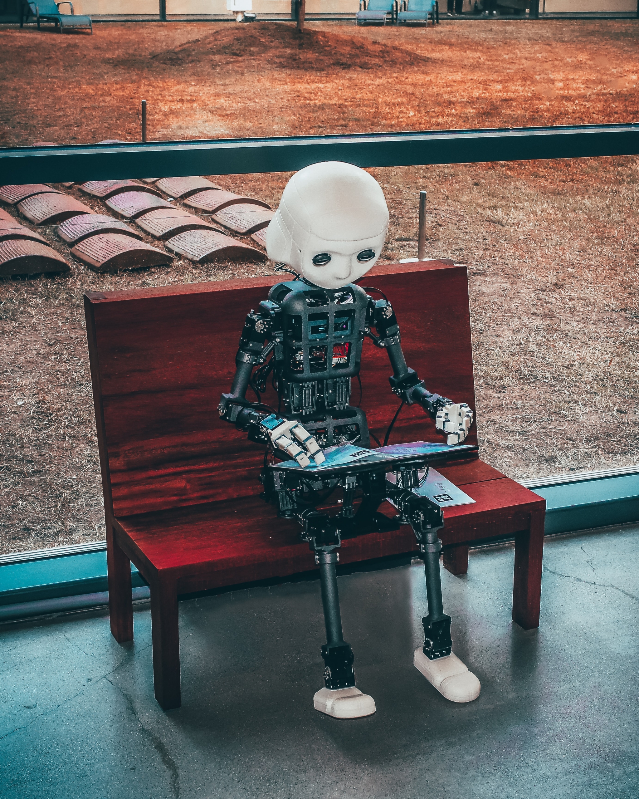 人型ロボットがベンチに座って、資料を見ている