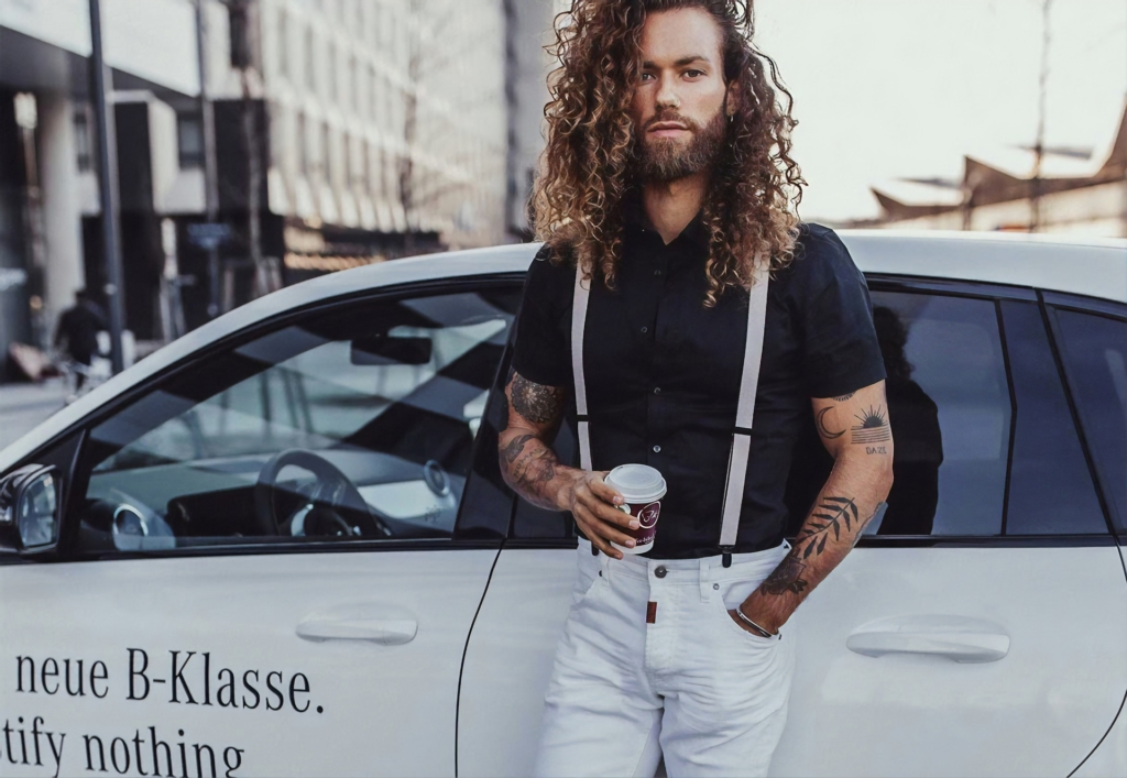 白い車の前でコーヒーを持つ男性