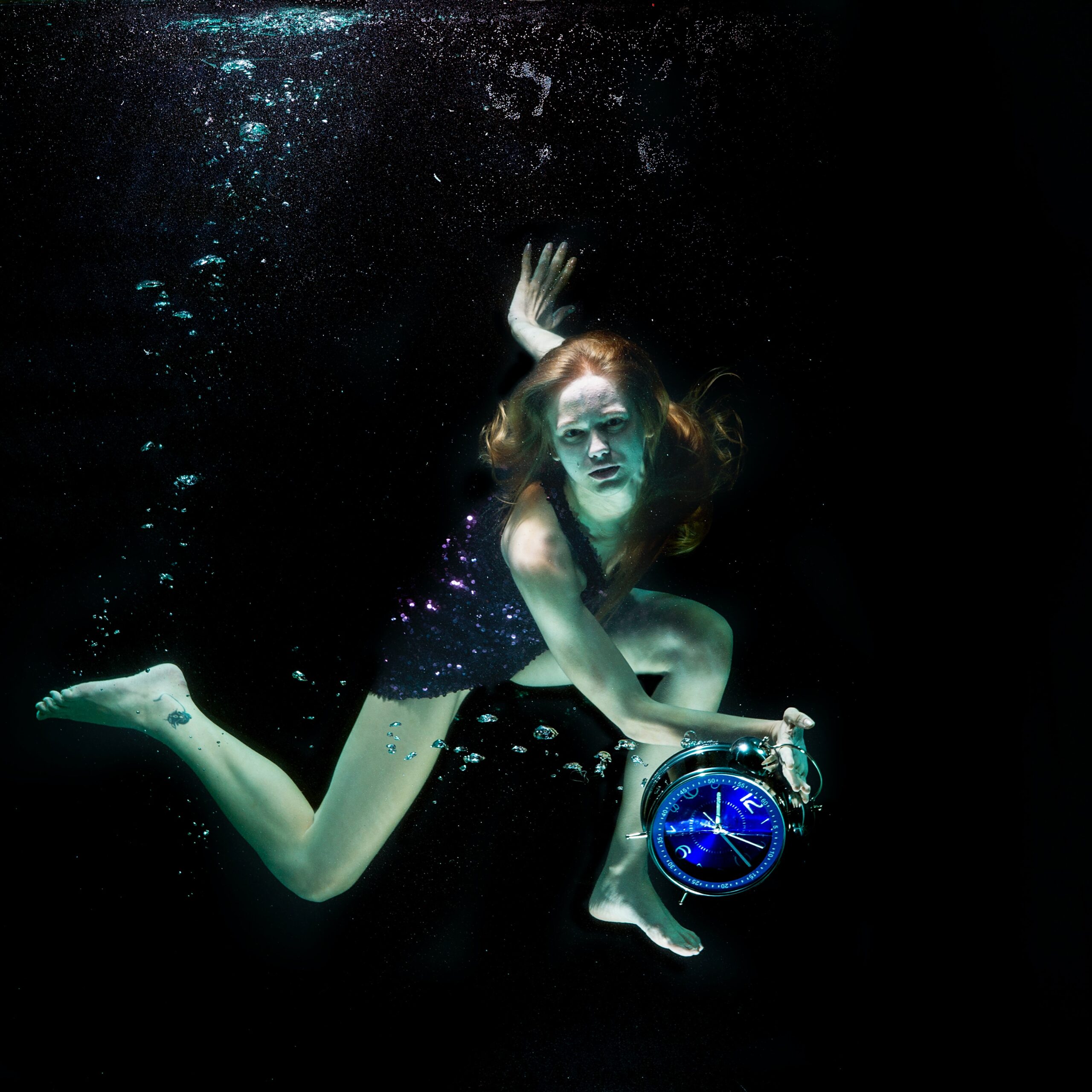 海中で時計を持つ女性